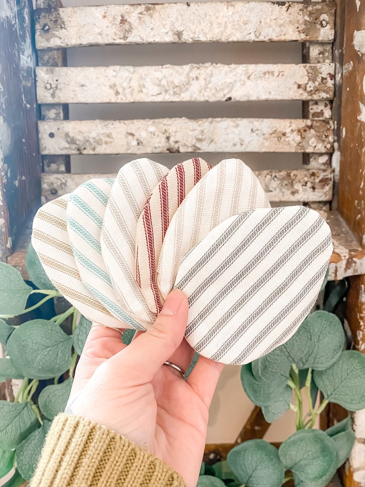 Hand holding six striped fabric easter eggs.