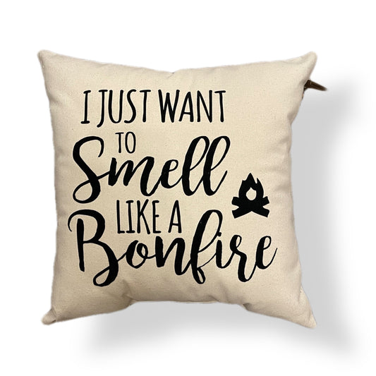 Beige pillow that says "I just want to smell like a bonfire" with a small campfire design
